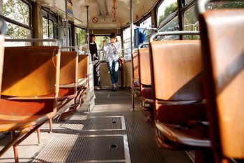 Zwei Frauen stehen in einer Straßenbahn und unterhalten sich, im Vordergrund leere Sitze