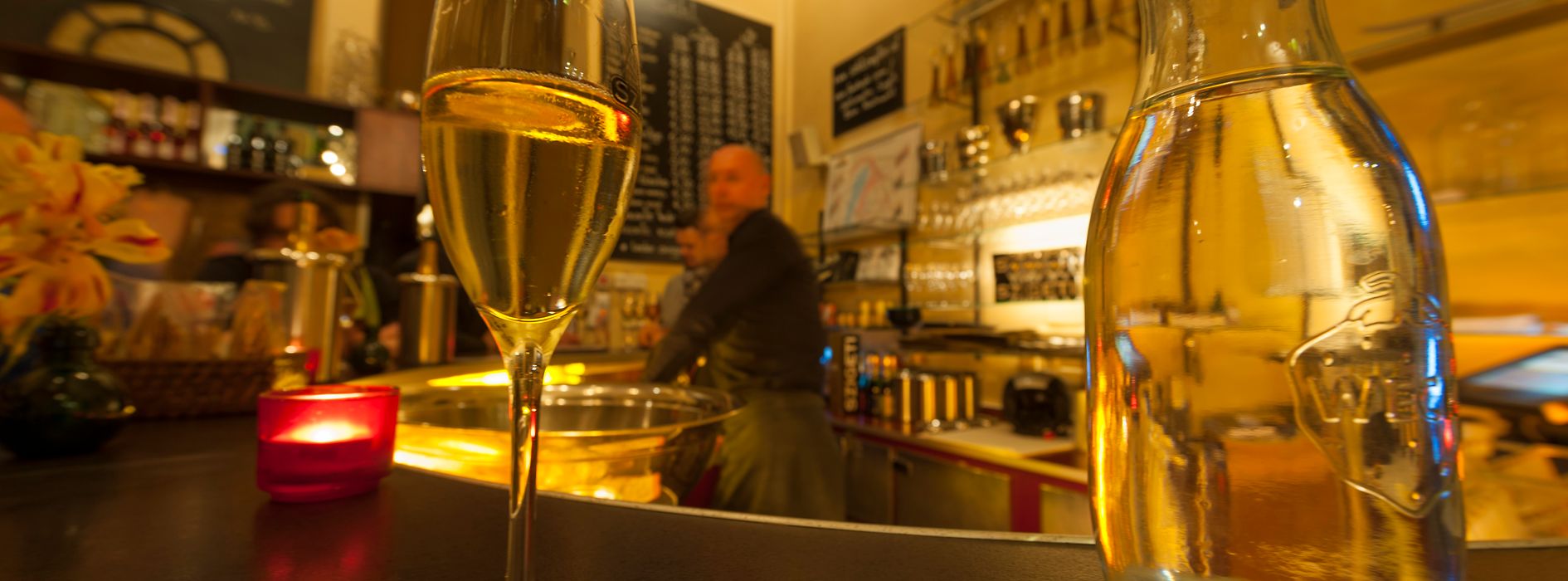 Szigeti pezsgőbolt, belső nézet egy pohár pezsgővel és vendégekkel 