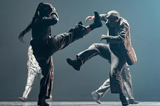 Mette Ingvartsen: Rush. A dancer wrapped in metal foil leans on a white table.