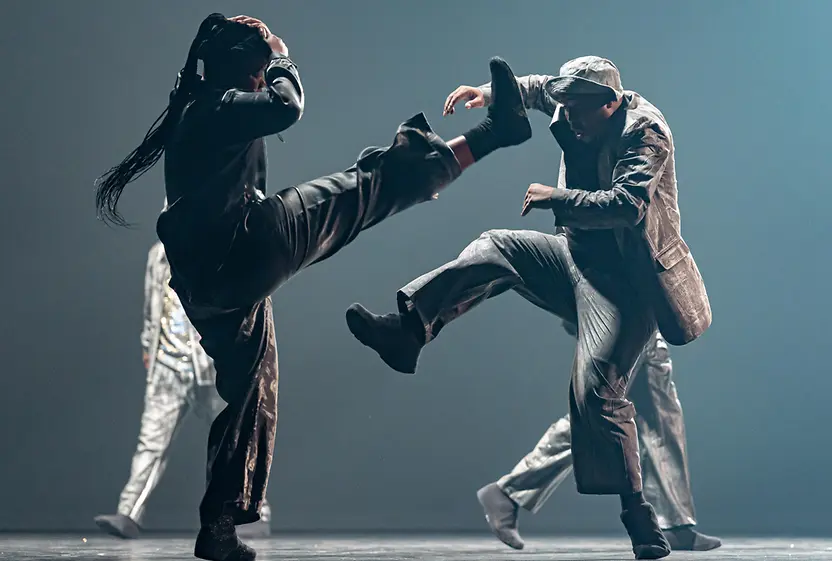 Mette Ingvartsen: Rush. A dancer wrapped in metal foil leans on a white table.