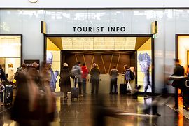 Tourist-Info am Flughafen Wien mit Reisenden im Vordergrund
