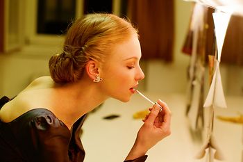 Woman putting on makeup in front of a mirror in the Opera Ball cloakroom