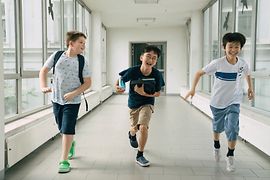 Three choristers running down a corridor in the school