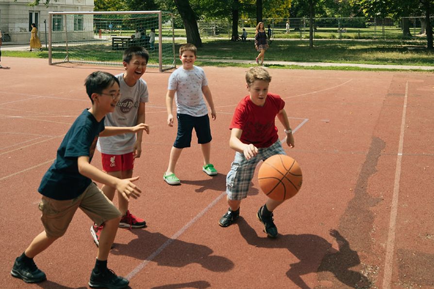Niños cantores juegan al baloncesto en una cancha del Augarten