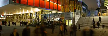 Wiener Stadthalle, abends mit Lichtern in gelb und rot, Besucher