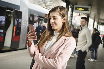 Students in a subway station looking at a mobile phone