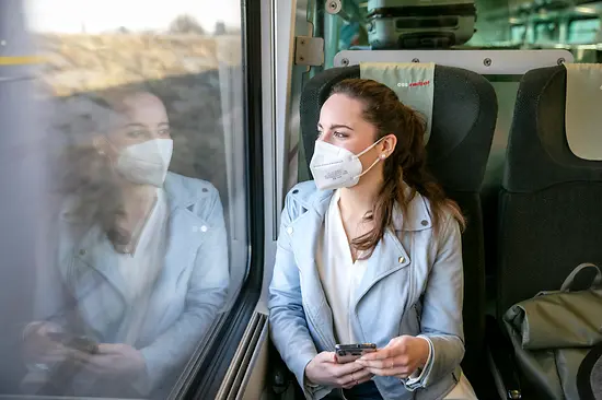 Una donna con mascherina FFP2 in treno