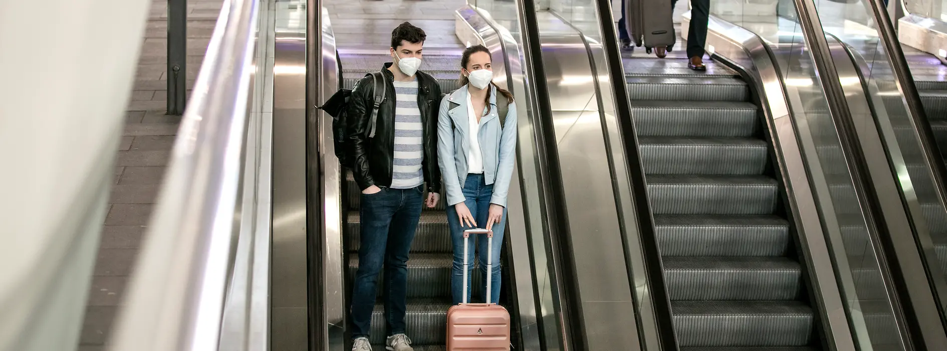 Menschen mit Masken am Bahnhof