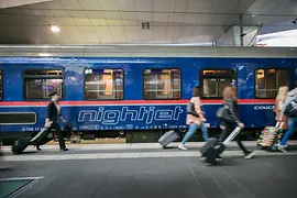 El Nightjet de la ÖBB en la estación de tren con viajeros de fondo