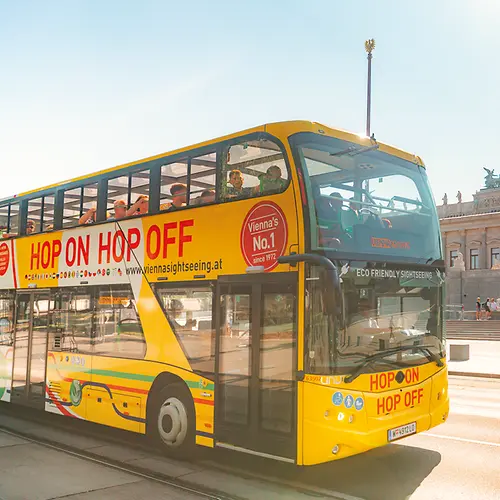 Several people getting on a yellow Hop-On Hop-Off double-decker bus of Vienna Sightseeing Tours
