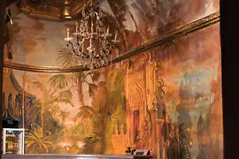 Бар с люстрой и обоями с изображением пальм в сауне Кайзербрюндль