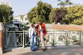 Una coppia su un ponte nel Parco cittadino, intenta a guardare lo schermo di uno smartphone
