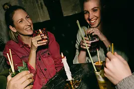 Négy személy itallal egy gyertyával díszített asztalnál