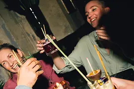 Čtyři lidé s nápoji u stolu se svíčkou