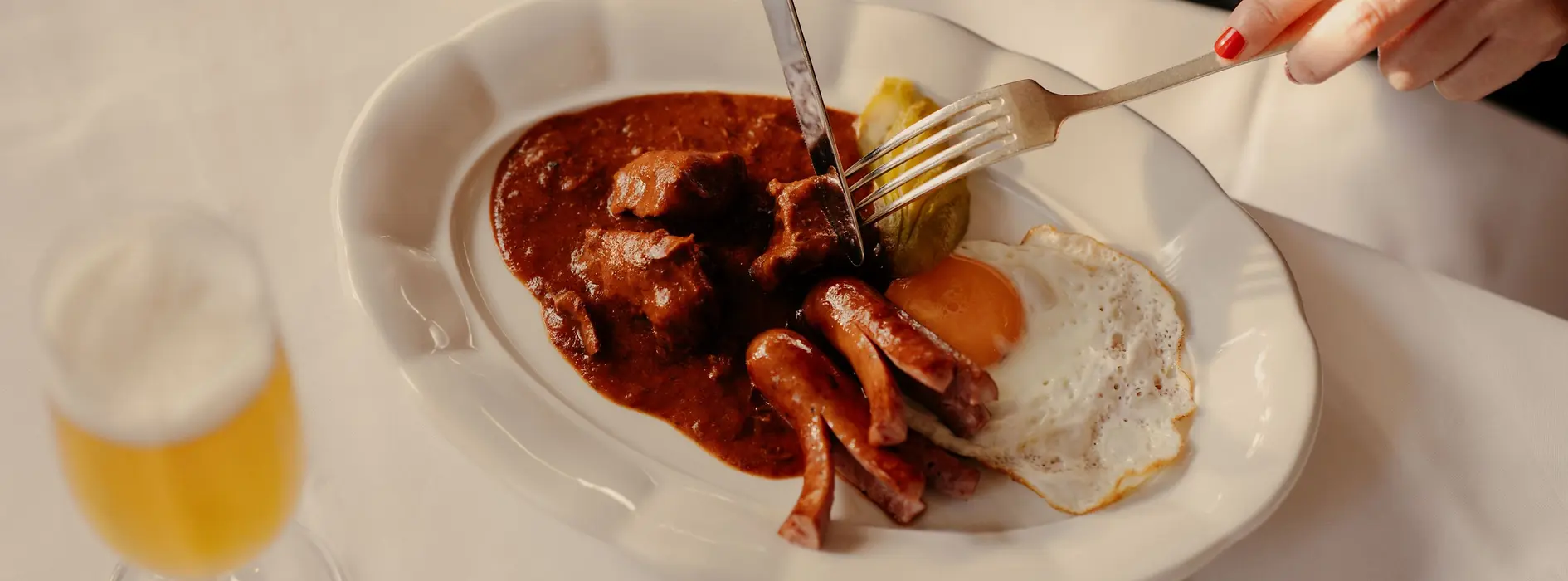 Ein Teller mit einem Fiakergulasch mit Salzkartoffeln, Spiegelei und einem Würstchen