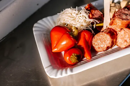 Geschnittene Wurst mit Pfefferoni auf einem Pappteller
