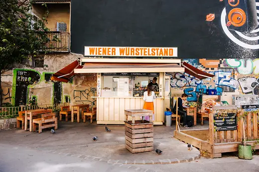 Ein Würstelstand mit Sitzmöbel davor