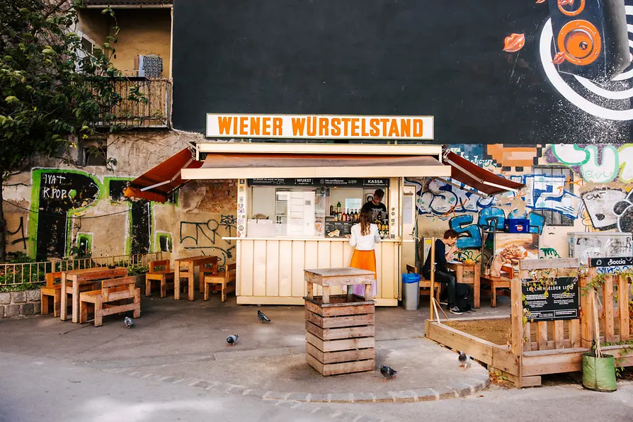 Ein Würstelstand mit Sitzmöbel davor