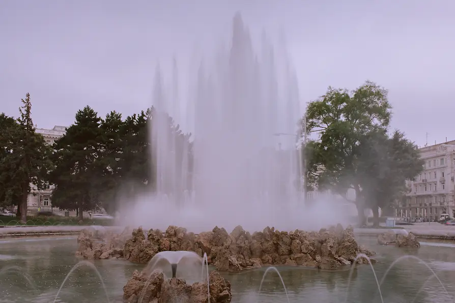 Le jet d'eau : une étendue d'eau devant des pierres autour d'un jet d'eau vertical