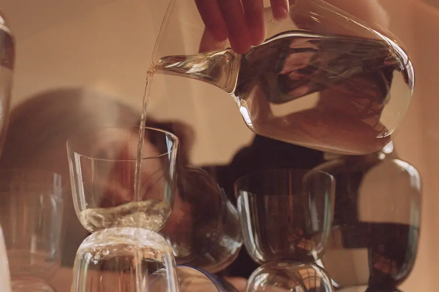Une femme verse de l'eau d'une carafe dans des verres