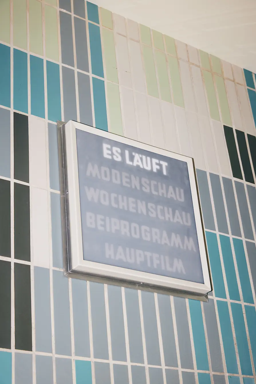 Gartenbaukino interior shot, light sign with wording \"ES LÄUFT\" (\"IT'S RUNNING\")