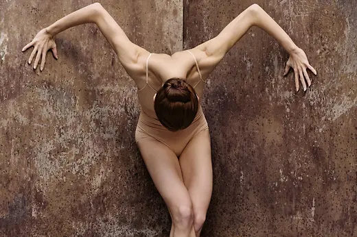 Danseuse dans une pose intense devant un mur couleur rouille, tirée de la production de ballet « Marie Antoinette »