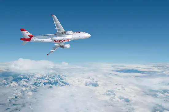 Avión blanco con la palabra «Servus» de Austrian Airlines sobrevolando las nubes