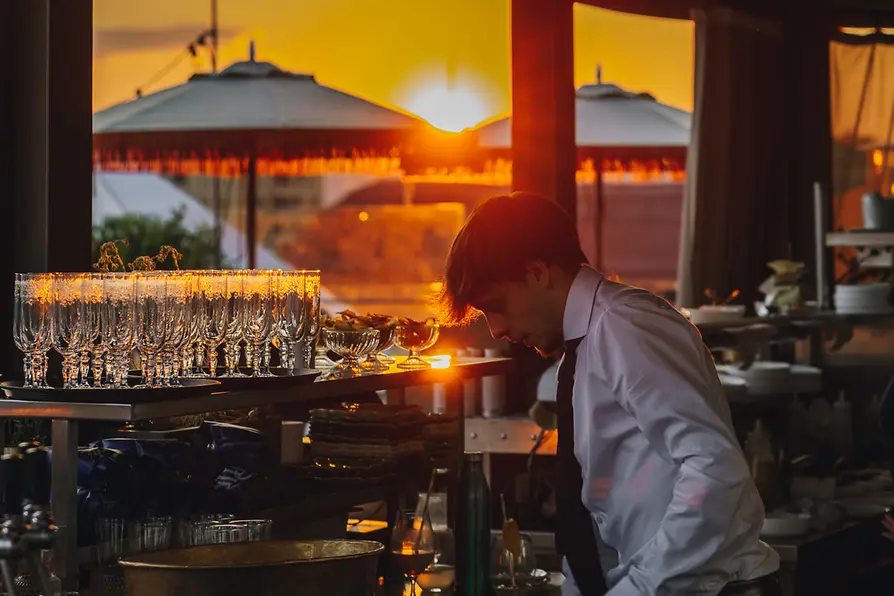Hote Motto Rooftop-Bar Chez Bernard, Barkeeper mischt Getränke, Sonnenuntergang im Hintergrund
