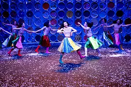 Koreanische Tänzer:innen wirbeln in bunten Röcken und Stiefeln auf der Bühne herum.