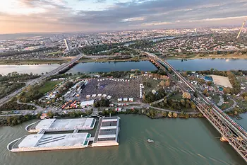 Luftaufnahme mit Blick auf die Donauinsel, auf der das Open Air Donauinselfest gerade stattfindet, alles ist voller Menschen, Bühnen und Zelte.