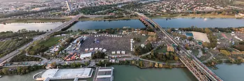 Luftaufnahme mit Blick auf die Donauinsel, auf der das Open Air Donauinselfest gerade stattfindet, alles ist voller Menschen, Bühnen und Zelte.