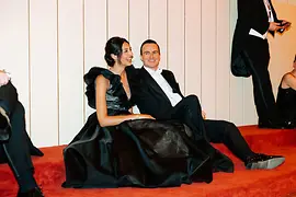 Pareja vestida de gala sentada en el suelo y recuperándose de bailar
