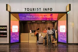 Tourist-Info am Flughafen Wien mit Reisenden im Vordergrund