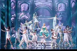 Maria Theresia in grünem Kleid, inmitten von Tänzerinnen und Tänzern in weißen Kostümen.