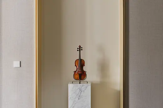 Geige auf einem Marmorsockel in einer hohen, runden Wandnische. 