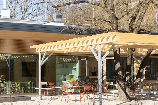 Überdachte Terrasse mit bunten Gartenmöbeln vor dem Empfangsbereich des Campingplatzes 