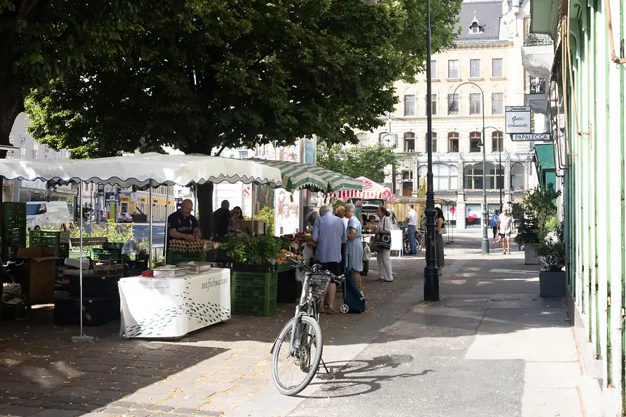 Scena di strada a Margaretenplatz a Vienna con bancarelle di mercato e una bicicletta parcheggiata