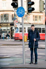 Blind person uses acoustic-tactile traffic light.