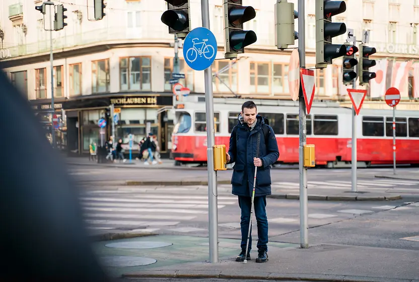 Blind person uses acoustic-tactile traffic light.